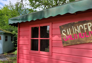 Twee kleurrijke houten huisjes bij vakantiepark Zomerlicht in Overijssel, Nederland, met Salinger- en Kerouac-bord.
