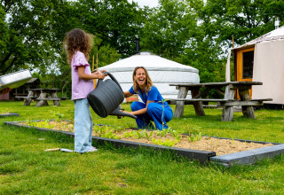 Twee mensen water geven aan planten in een moestuin bij een vakantiepark in Overijssel, Nederland.