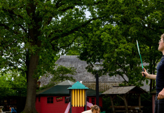 Twee mensen in een groene tuin bij Zomerlicht vakantiepark in Overijssel, Nederland, met bomen op de achtergrond.