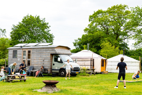 Vakantiegangers bij Zomerlicht, Overijssel, Nederland, genieten voor tiny house en yurts op groen grasveld.