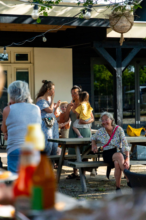 Mensen genieten van een zomerse bijeenkomst buiten bij Zomerlicht vakantiepark in Overijssel, Nederland.