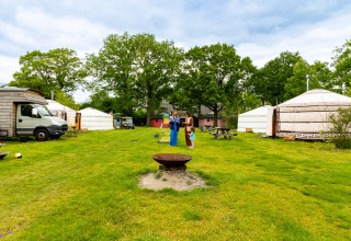 Gezellige vakantiepark Zomerlicht in Overijssel met yurts, picknicktafels en mensen op een grasveld.