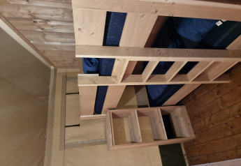 Interior of a Safari tent with a wooden bunk bed and floor at Camping Bockenauer Schweiz in Germany.
