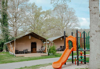 Tenda safari con servizi privati al Camping de Haer nei Paesi Bassi, con parco giochi e natura verde.