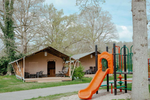 Safari-Zelt mit eigenem Bad auf Camping de Haer in den Niederlanden, mit Spielplatz im Vordergrund.
