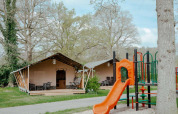 Safari-Zelt mit eigenem Bad auf Camping de Haer in den Niederlanden, mit Spielplatz im Vordergrund.