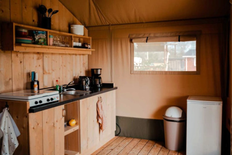 Knusse keuken in een safaritent met houten wanden, keukengerei en raam bij Camping de Haer, Nederland.