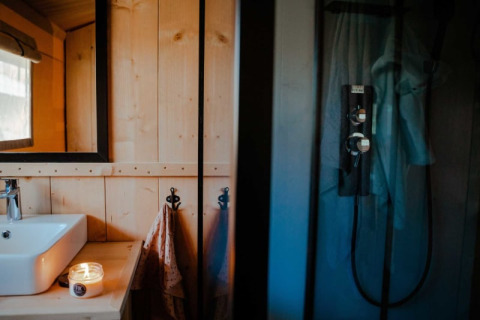 Moderne badeværelse i safaritelt med håndvask, spejl, lys tændt og bruser ved Camping de Haer, Holland.