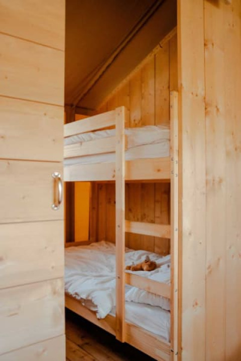 Et hyggeligt soveområde i en safariteltskabine med køjesenge og trævægge, Safari tent + sanitary.
