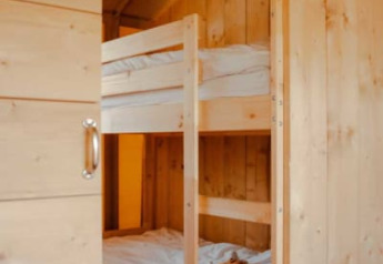 Gemütlicher Schlafbereich in einem Safarizelt mit Etagenbetten und Holzvertäfelung, Safari tent + sanitary.