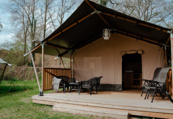 Tienda safari con baño privado sobre tarima de madera, asientos al aire libre en entorno natural