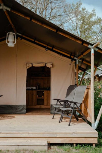 Safari-Zelt mit Terrasse und Stühlen auf Camping de Haer, Niederlande. Eingedeckte Zelteingang.
