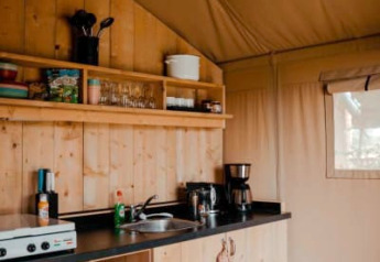 Kleine, gezellige keuken met houten kasten in safaritent op Camping de Haer in Nederland.