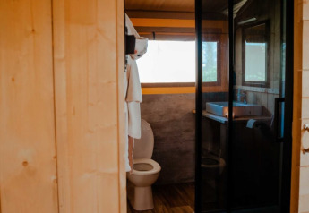 Indvendigt billede af badeværelset i et safaritelt med toilet og håndvask ved Camping de Haer, Holland.