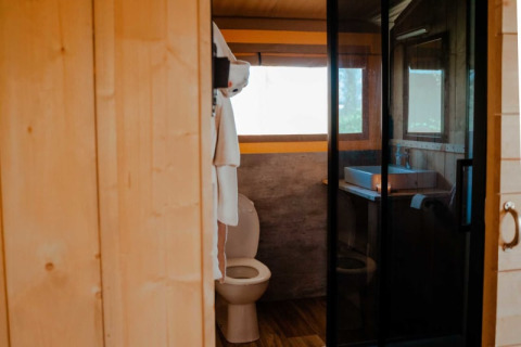 Interior view of bathroom in safari tent featuring toilet and sink at Camping de Haer, Netherlands.