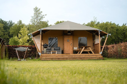 Safari tent Villatent Cottage at Holiday Park Ackersate, Netherlands, with porch, bench and barbecue grill.