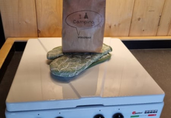 Sacchetto di carta e presine su un fornello in una tenda safari rivestita in legno nei Paesi Bassi.