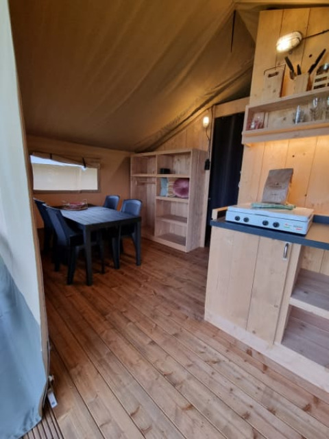 Interior of a safari tent with wooden furniture and dining table at Camping de Tulpenweide, Netherlands.