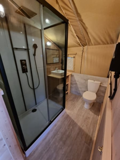 Badkamer in een safaritent bij Camping de Tulpenweide in Nederland met douche en toilet zichtbaar.