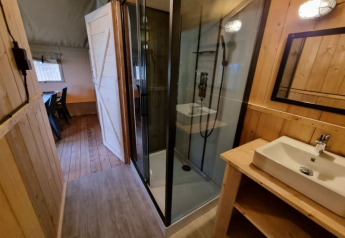 Bagno in tenda safari con doccia e lavandino al Camping de Tulpenweide nei Paesi Bassi.