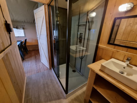 Salle de bain sous tente safari avec douche et lavabo au Camping de Tulpenweide aux Pays-Bas.