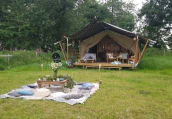 Safari-Zelt bei Glamping des 2 Marguerites in Frankreich, im Grünen mit gemütlicher Picknick-Ecke davor.