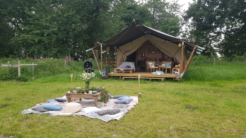 Tienda safari en Glamping des 2 Marguerites, Francia, con área de picnic sobre césped frente a la tienda.
