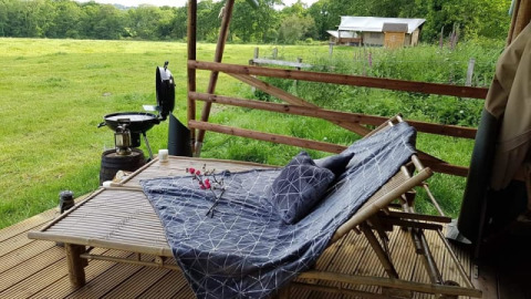 Udendørs afslapningsområde ved Safari Tent på Glamping des 2 Marguerites, Frankrig, med udsigt over marken.