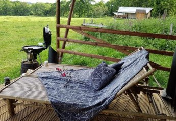 Udendørs afslapningsområde ved Safari Tent på Glamping des 2 Marguerites, Frankrig, med udsigt over marken.