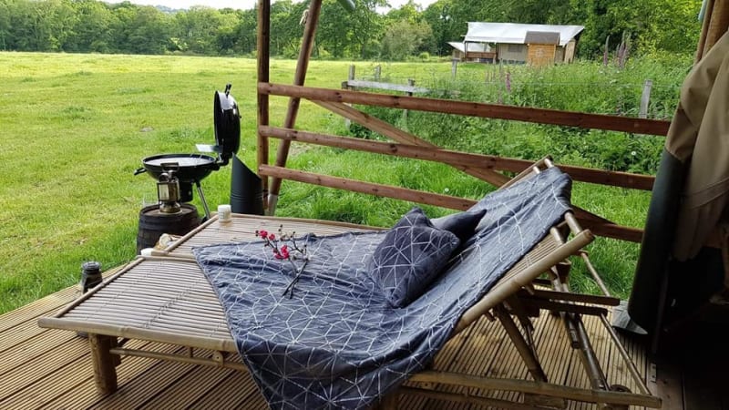 Buitenlounge bij Safari Tent op Glamping des 2 Marguerites, Frankrijk, met uitzicht op het veld en ligstoelen.