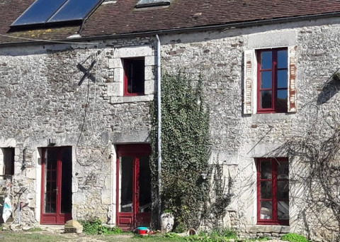 Casa de piedra con marcos de ventana rojos y plantas trepadoras en Safari tent en Glamping des 2 Marguerites en Francia.