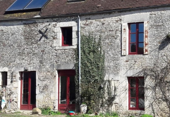 Steinhaus mit roten Fensterrahmen und Kletterpflanzen an der Fassade bei Safari-Zelt auf Glamping des 2 Marguerites in Frankreich.