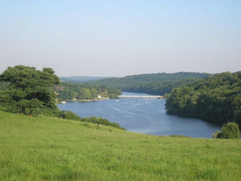 Vue paisible sur la rivière, champs verts et forêt depuis la tente safari au Glamping des 2 Marguerites, France.