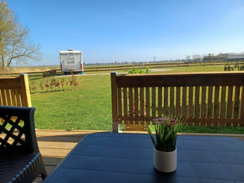 Blick von einer Safarizelt-Terrasse auf Camping de Noorde in den Niederlanden mit Wohnmobil und Wiese.