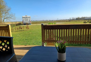 Vista desde la terraza de una tienda safari en Camping de Noorde, Países Bajos, con césped y caravana.