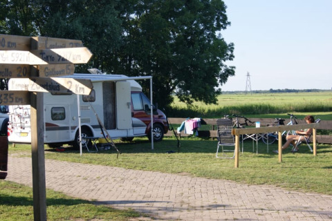 Tienda safari en Camping de Noorde, Países Bajos, con autocaravana, bicis y huésped relajándose.
