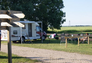 Tienda safari en Camping de Noorde, Países Bajos, con autocaravana, bicis y huésped relajándose.