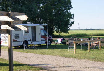 Tienda safari en Camping de Noorde, Países Bajos, con autocaravana, bicis y huésped relajándose.
