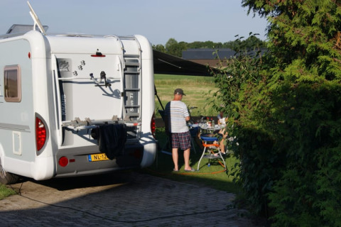 Wohnmobil und Menschen beim Picknick neben einem Safari-Zelt auf Camping de Noorde in den Niederlanden.