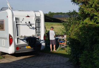 Kampeerwagen en mensen die buiten eten bij een safaritent op Camping de Noorde in Nederland.