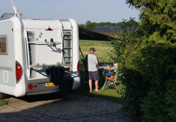 Camper e persone che cenano all'aperto vicino a una tenda safari presso il Camping de Noorde nei Paesi Bassi.