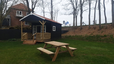 Safari telt ved Camping de Noorde i Holland, med træhytte og picnicbord på græsplæne omgivet af træer.