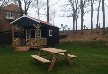 Safari tent at Camping de Noorde in the Netherlands, featuring a wooden cabin, picnic table, and grassy yard.