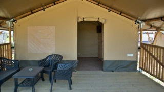Tienda safari con terraza de madera cubierta y muebles de exterior en Minicamping de Vrolijke Flierefluiter, Países Bajos.