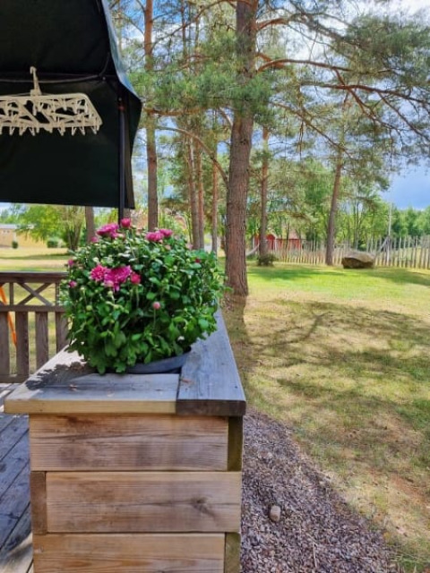 Zicht vanaf een safaritentterras met bloempot, bomen en tuin op een rustige camping.