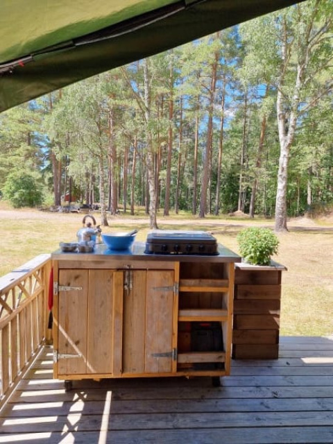 Buitenkeuken bij safaritent met eigen sanitair, omgeven door bomen in een rustgevend boslandschap.