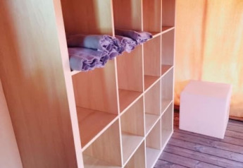 Estante con toallas en el interior de una tienda safari, con suelo de madera y luz natural.