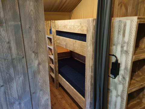 Interno di una tenda safari con letti a castello in legno al Camping het Horstmannsbos nei Paesi Bassi.