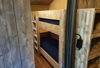 Interior of a safari tent with wooden bunk beds and floor at Camping het Horstmannsbos in the Netherlands.