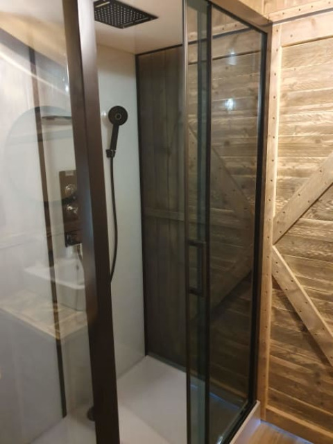 Moderne douche met glazen deur en houten wand in een safaritent op Camping het Horstmannsbos, Nederland.